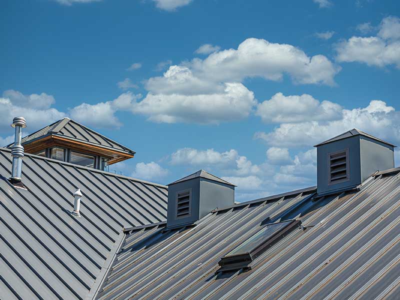 Top view of a large sloped commercial roof with a gray metal roofing system